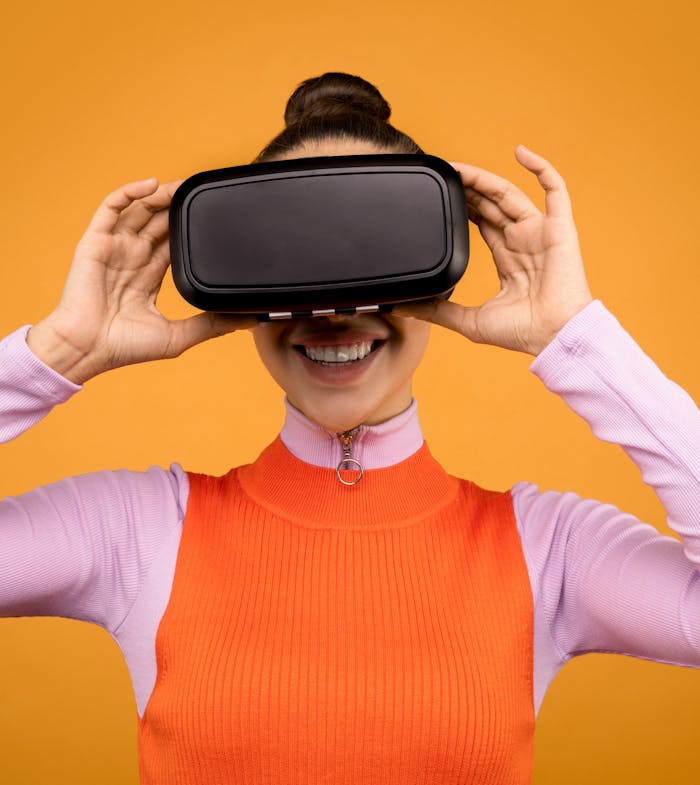 Smiling woman wearing a VR headset against a vibrant orange background.